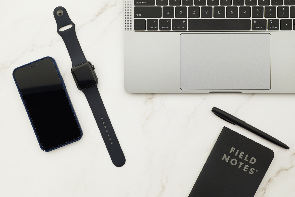 Laptop, phone, smart watch and a notebook arranged on a marble desk