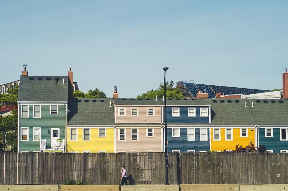 Row of colorful townhouses with wooden fences seen from across the street